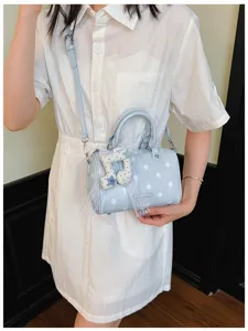 Light blue polka dot boston handbag with shoulder strap and cute pendant details.