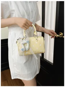 Stylish yellow polka dot handbag for women, chic pillow shoulder bag with cute pendant.