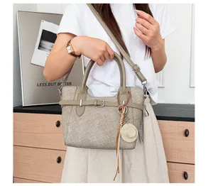 Canvas shoulder handbag detail showing stylish retro design with strap and straw hat charm.