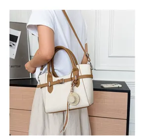 Detail view of stylish color-blocking women shoulder bag with cute straw hat pendant.