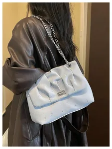 Élégant sac à épaule bleu avec motif étoiles lune, bandoulière chaîne et fermoir tournant.