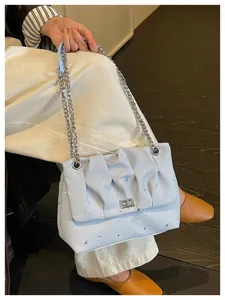 Gros plan détaillé du sac à épaule bleu clair avec imprimé céleste et chaîne métallique.
