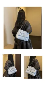 Vue détaillée du sac à bandoulière bleu clair montrant son design plissé unique et sa chaîne.