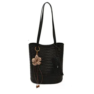 Classic black woven leather bucket tote bag featuring a cute floral charm and long shoulder strap.