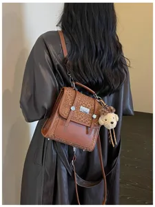 Detail shot of brown leather backpack featuring leopard print flap and cute plush bear pendant.