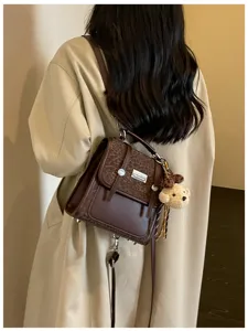 Chic college style womens brown backpack, retro bookbag with cute bear charm for daily use.