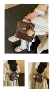 Close-up detail of retro college-style brown mini backpack with cute bear pendant.