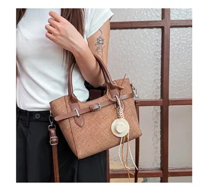 Detail view of a retro brown fabric handbag with PU leather trim, metal buckle and cute straw hat charm.