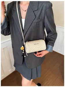 Gedetailleerd overzicht van stijlvolle geweven kussen crossbody tas met schattige pompon.