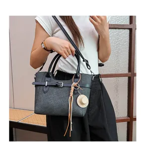 Detailed view of stylish dark gray women shoulder bag with elegant belt decoration and pendant.