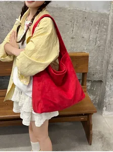 Vue détaillée du sac porté épaule rouge en suédine souple montrant sa texture et grande capacité.