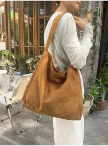 Vue détaillée du sac cabas souple en suédine marron, porté à l'épaule dans un style urbain chic.
