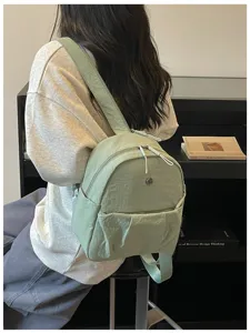 Light green minimalist casual backpack detail view showing compact size and commuter style.