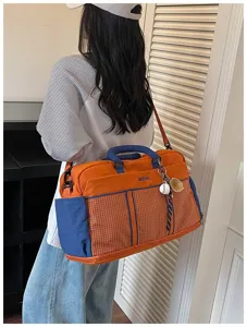 Large capacity travel duffel bag with stylish orange and blue color block design and shoulder strap.