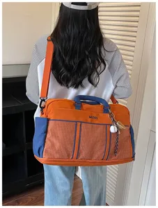 Detailed view of large capacity orange blue travel duffel bag with grid front pocket and strap.