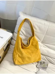 Vue détaillée du sac porté épaule hobo en suédine jaune sur un coussin blanc confortable.