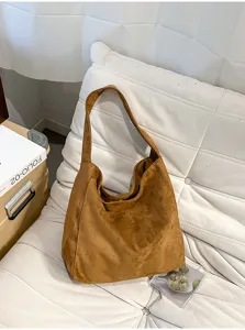 Vue détaillée du sac porté épaule en suédine marron posé sur un coussin blanc, style de vie.