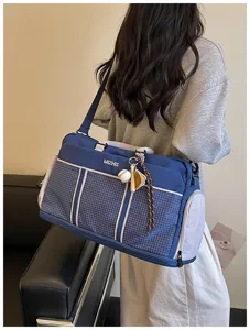 Detail view of large capacity travel duffel bag in blue grid style with shoulder strap.