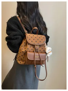 Stylish brown polka dot backpack with leather details and cute charm, perfect for daily commute.