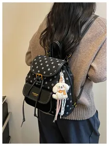 Stylish black polka dot backpack with plush puppy charm, casual leather daypack for women.