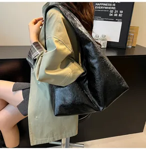 Dettaglio borsa a spalla in pelle cerata nera, design vintage slouchy hobo per lavoro.