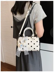 White polka dot Boston handbag detail view, featuring cute lace doll pendant and shoulder strap.