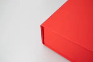 Close up view of red gift box corner, folding box detail showing textured paper finish.