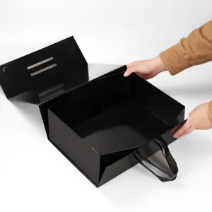 Boîte cadeau pliante noire avec fermeture magnétique et poignée ruban pour emballage.