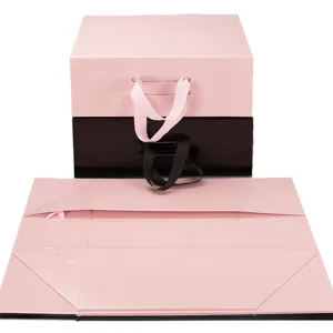 Boîte cadeau pliable avec poignées en ruban et fermeture magnétique rose et noire.