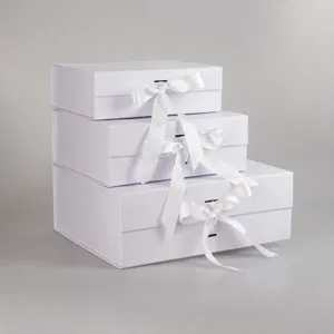 White folding gift boxes with ribbons, elegant packaging boxes for apparel suits and luxury gifts.