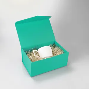 Coffret cadeau magnétique cyan avec tasse en céramique blanche et calage, présentation.