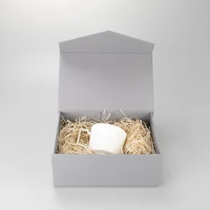 Weißer Keramikbecher mit eckigem Griff im grauen Geschenkkarton mit Holzwolle-Füllung.