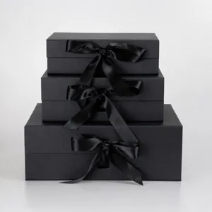 Luxury black gift boxes with satin ribbon bows, premium rigid boxes for apparel packaging.