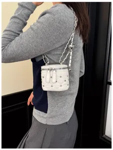 Gedetailleerde opname van een witte gewatteerde mini-boxtas met strass-steentjes en ketting.
