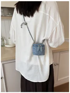 Gedetailleerd overzicht van de mini denim gewatteerde tas met ketting en strass-steentjes.