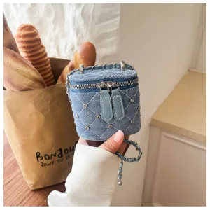 Close-up van blauwe denim gewatteerde mini box tas met strass steentjes en kettingdetail.