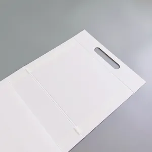Détail de la boîte en carton blanc pliable avec poignée découpée et structure pliée soignée.