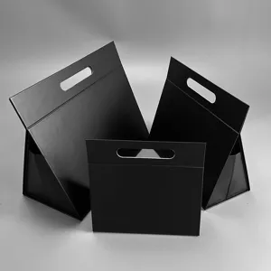 Detailaufnahme schwarzer dreieckiger Faltgeschenkboxen mit praktischem Griff und stabilem Design.