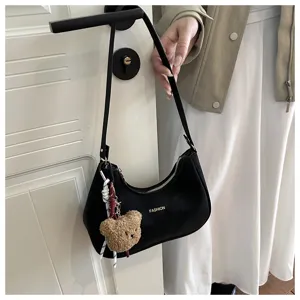 Vista dettagliata della borsa a spalla nera chic sotto l'ascella con grazioso ciondolo in peluche.