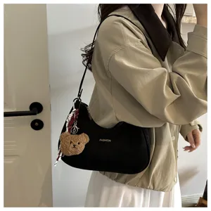 Vista dettagliata della borsa a spalla nera minimalista con grazioso ciondolo orsetto di peluche.