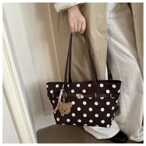 Vista dettagliata di una borsa tote marrone a pois vintage con ciondolo a orsetto.