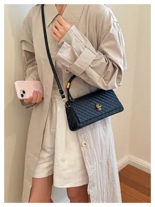 Detailed view of a stylish black woven crossbody bag worn by a model in casual outfit.