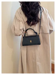 Stylish black woven leather shoulder bag with top handle and gold lock for daily commute.