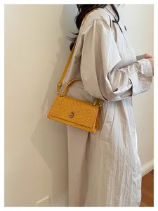 Detailed view of the yellow woven shoulder handbag showcasing its premium texture and clasp.