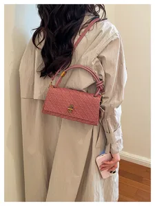 Detail view of pink woven shoulder bag with metal lock, stylish commuting accessory.