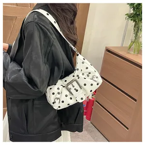 Foto de detalle de un elegante bolso de hombro blanco con lunares y hebilla en modelo.
