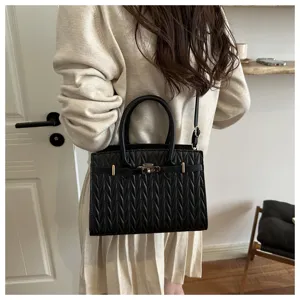Vista dettagliata di una borsa a tracolla nera trapuntata con eleganti finiture metalliche dorate.