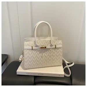 Elegante borsa a mano bianca trapuntata con manico superiore, dettagli dorati e tracolla.