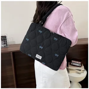 Detailed view of the black quilted laptop shoulder bag featuring cute blue bow embroidery design.