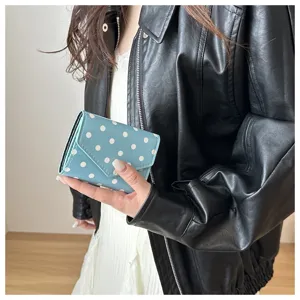 Primo piano del grazioso portafoglio a pois che mostra il design pieghevole blu e la trama.